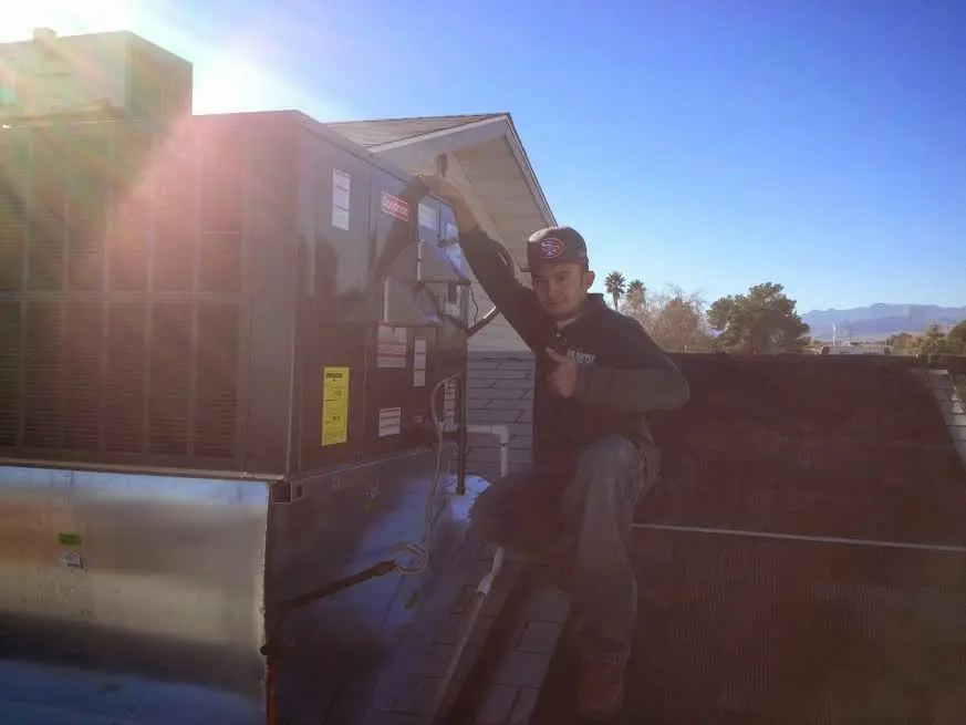 HVAC technician performing Air Duct Cleaning on a rooftop unit in Bernards